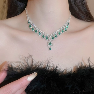Detail of V-shaped silver necklace with green teardrop gemstones and tassel diamonds