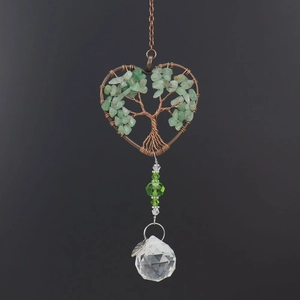 Close-up of heart-shaped tree of life suncatcher with green stones and crystal ball