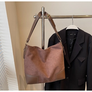 Detail of suede and leather stitching on dark brown tote bag with white contrast seams