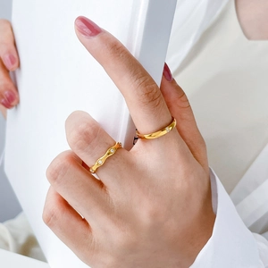 Close-up of gold-plated rings with wave design and white cubic zirconia on a hand