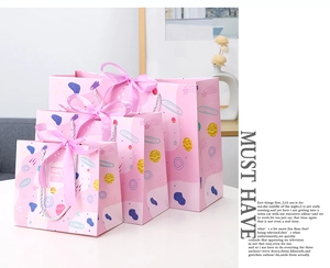 Detailed view of pink gift bags with star patterns, silk bows and woven handles