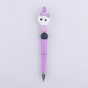 Close-up of purple beaded pen with cartoon skull silicone topper and glitter finish