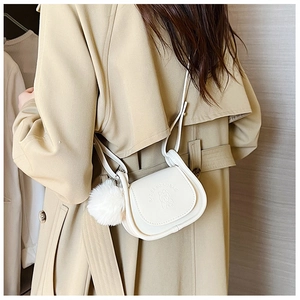 Detailed side view of white mini crossbody bag with embossed dog logo and plush ball