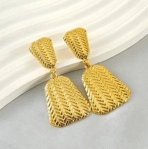 Detail of gold-plated geometric earrings featuring a woven texture and tiered design