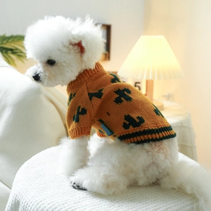 Detail of orange knitted dog sweater with green patterns and ribbed cuffs on a white dog
