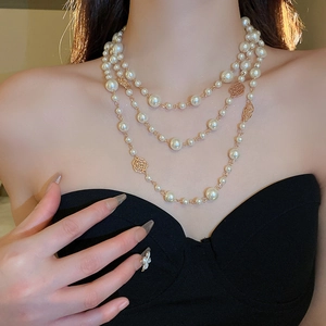 Detail of layered pearl necklace with gold rose accents on a black dress backdrop
