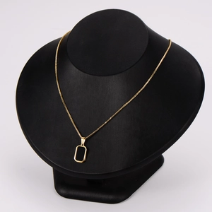 Minimalist gold necklace with a black rectangular pendant on a stylish display bust