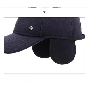 Detailaufnahme der dunkelblauen Woll-Wintermütze mit Ohrenklappen und Logo aus Metall