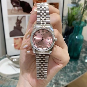 Close-up of women's stainless steel watch with pink dial, date window, and crystal markers