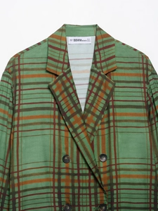 Détail d'un blazer à carreaux verts avec boutons croisés et texture en tissu sergé fin