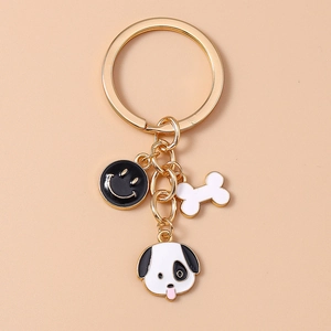 Golden keychain with black smiley face, white bone charm, and spotted dog head pendant