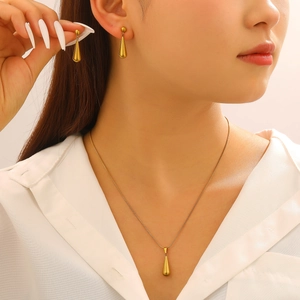 Elegantes Set aus goldener Tropfenkette und Ohrringen an einem weiblichen Model