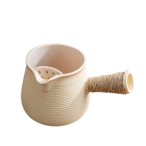Beige ceramic roasted milk tea pot with twine handle and integrated filter on white background