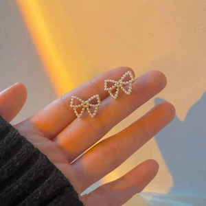 Close-up of elegant pearl bow earrings featuring gold-tone finish and delicate design