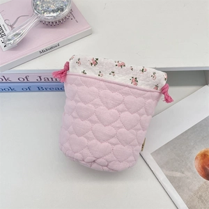 Detail of pink quilted drawstring storage bag with heart pattern and floral trim
