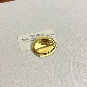 Detailed close-up of a gold irregular pebble brooch with a polished mirror finish