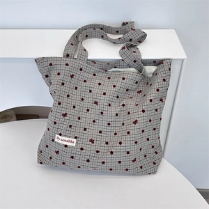 Détail du sac cabas en toile montrant des pois rouges et une broderie de nœud délicate