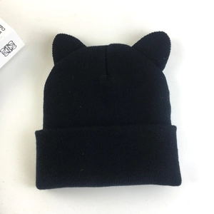 Detail shot of the thick knitted texture and cute cat ear design on a black beanie