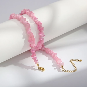 Macro shot of pink cat eye stone bead necklace with golden lobster clasp and chain