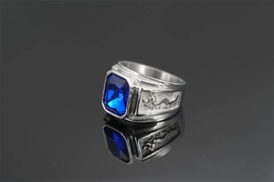 Close-up of dragon relief on silver steel ring with rectangle blue gemstone inlay