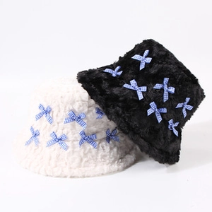 Détails de bobs en peluche noir et blanc ornés de petits nœuds à carreaux bleus