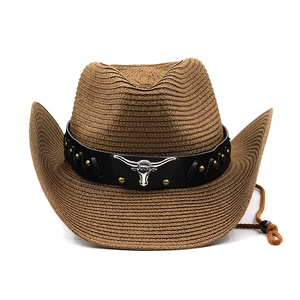 Detail of straw cowboy hat featuring a black band with silver bull head and gold studs