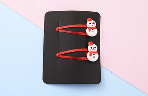 Detail of two Christmas snowman hair clips with red glitter base on display card