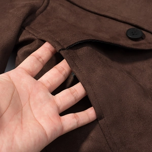 Detail of brown faux suede coat featuring side pocket, stitching, and black resin button