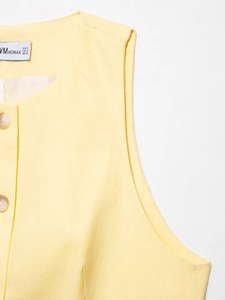 Detail of yellow linen vest showing neckline, buttons, and fabric texture with VMVOMAN label