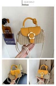 Détail d'un sac en paille jaune avec boucle florale dorée et poignée nouée