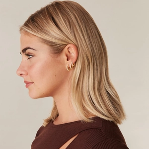 Three-piece set of gold hoop earrings with sparkling cubic zirconia on a female model