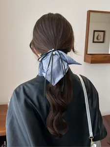Détail d'un chouchou bleu clair scintillant avec perle blanche et ruban noir sur cheveux