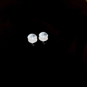 Macro shot of transparent burger-shaped earring back stoppers on a black background