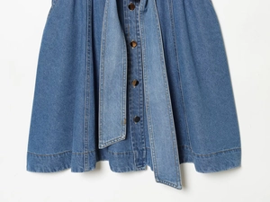 Detail eines blauen Jeans-Hemdkleides mit Metallknöpfen, Gürtel und sichtbaren Nähten