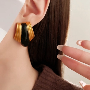 Close-up of a vintage black enamel and gold fan-shaped earring on a model