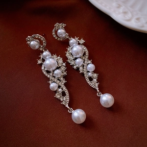 Macro detail of silver long drop earrings with inlaid rhinestones and faux pearls