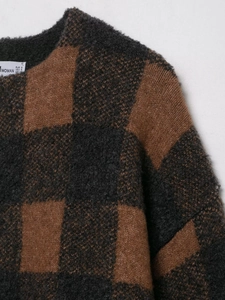Detailed close-up of brown and dark grey checkered knit fabric texture and soft crew neckline