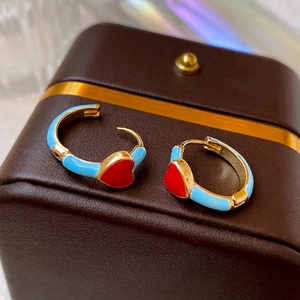 Minimalist red heart gold earrings with sky blue enamel finish shown on jewelry leather box
