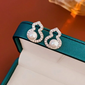 Elegant silver gourd earrings with pave zirconias and round pearls on velvet display
