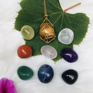 Polished natural crystal set with golden mesh necklace on a decorative green leaf