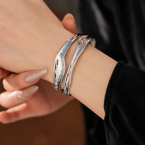 Close-up of irregular double-layer silver wavy cuff bracelet worn on female wrist