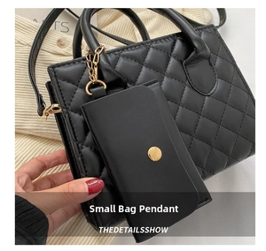 Detail of a black quilted mini coin purse charm with gold chain on a leather handbag