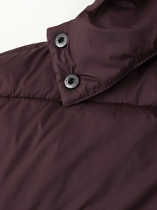 Detailed close-up of dark burgundy puffer jacket featuring premium fabric and metal snap buttons