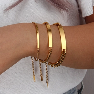Detailed view of layered 18K gold Cuban bracelets featuring polished blank metal plaques