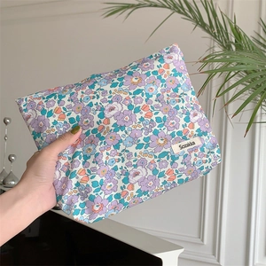 Macro detail of purple floral cotton pouch with small white brand tag and soft hand feel
