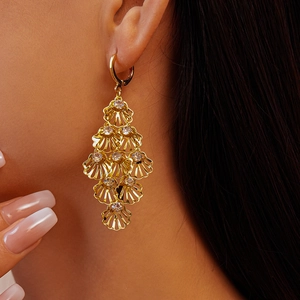 Detail of layered gold shell earrings with inlaid rhinestones shown on a model