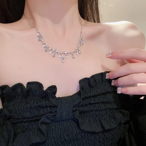 Close-up of a silver branch necklace with diamond teardrop pendant worn by a model