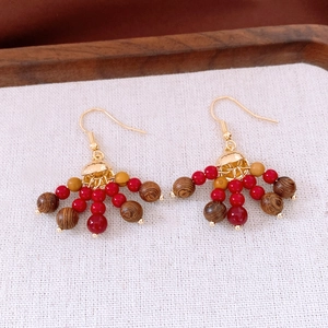 Détail de boucles d'oreilles bohèmes avec perles de verre rouges et bois texturé