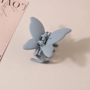 Détail d'une pince à cheveux papillon gris mat avec texture givrée et ressort solide