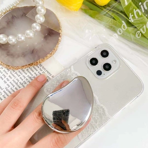 Close-up of silver teardrop mirror phone grip on a clear glitter case with stylish props
